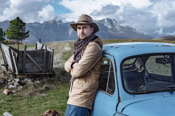 Voyageur à côté de la vieille voiture bleue sur le fond de belle — Photo