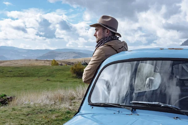 Voyageur à côté de la vieille voiture bleue sur le fond de belle — Photo