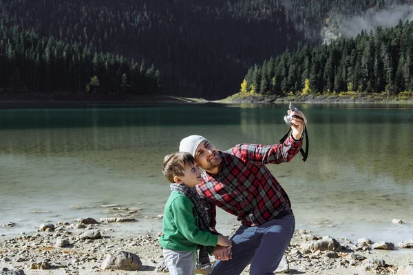 Viajante bonito com filho tirando foto no lago preto, Monte — Fotografia de Stock