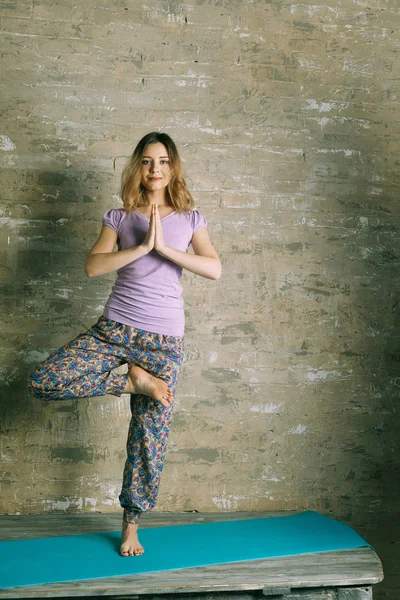 Mujer joven practicando en un estudio de yoga . — Foto de Stock