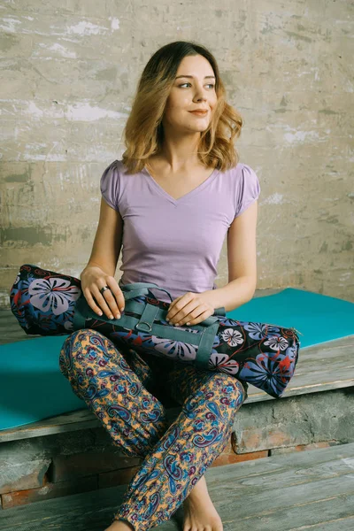 Jovem mulher atraente segurando tapete de ioga — Fotografia de Stock