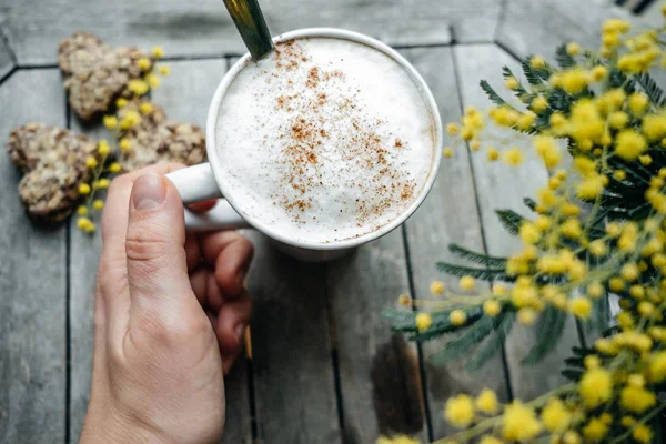 Cappuccino ile kadının eliyle tarçın hea ile beyaz kupa — Stok fotoğraf