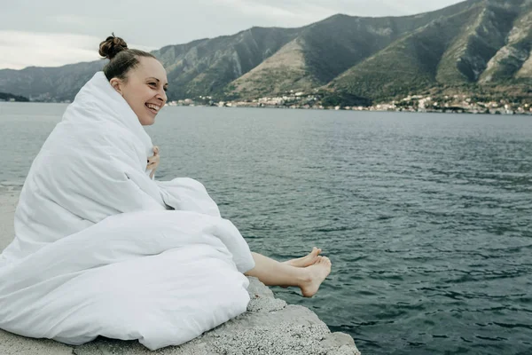 Usmívající se žena skrývá bílá deka stojícího na molu blízko s — Stock fotografie