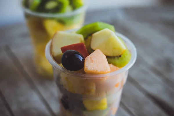 Frutos cortados: kiwi, abacaxi, tangerinas, maçãs, melão em plástico — Fotografia de Stock