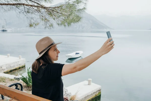 Travel woman in a hat making selfie at view of the bay in Monten — Stock Photo, Image