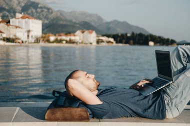 Rahatlatıcı ve dizüstü bilgisayar üzerinde çalışan yakışıklı delikanlı 