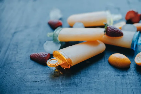 Paletas de yogur caseras con fresas y kumquat en un bla — Foto de Stock