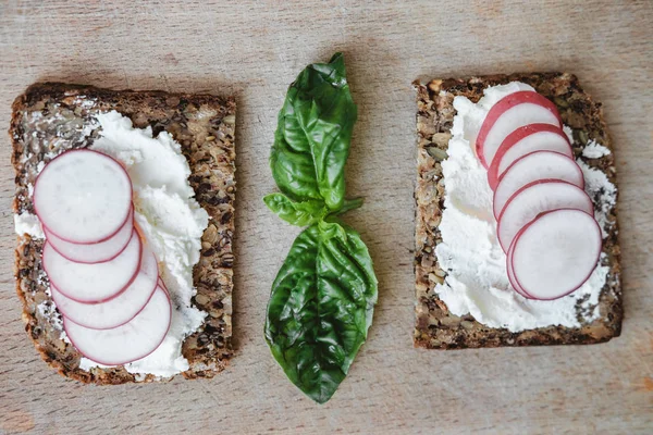 Dos piezas de pan con requesón, rábano y albahaca en rus — Foto de Stock