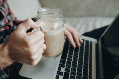 Hipster adam kırmızı Kareli gömlekli dizüstü kullanarak ve cof içme