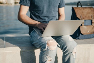 Denize yakın oturan dizüstü bilgisayar ile çalışan adam ellerini yukarıya kapatmak