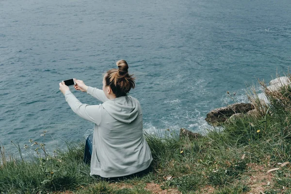 Jonge vrouw in een groen jasje foto nemen op de zee van het mou — Stockfoto