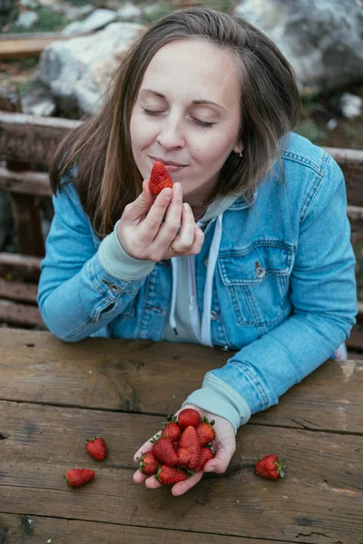 Jovem olhos fechados mulher comendo morangos na natureza em um b — Fotografia de Stock