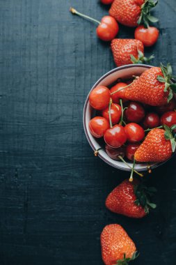 Dikey fotoğraf taze kiraz ve çilek siyah ahşap üzerine