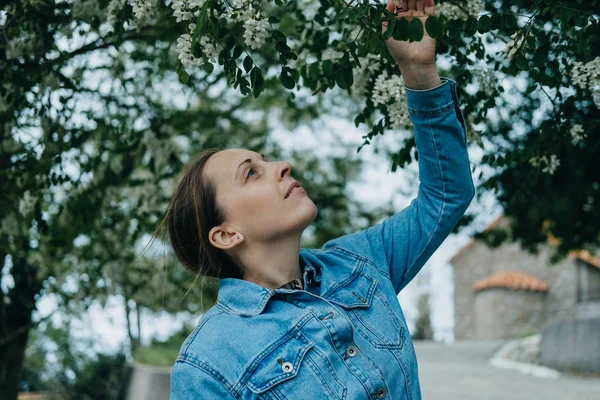 Mladá žena čichání akátu na jaře — Stock fotografie