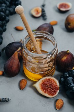 Karanlık closeup üzüm, incir, bal ve badem üzerinde gri bir backgr