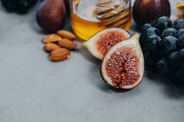 Kara üzüm, incir, bal ve gri arka plan üzerinde badem