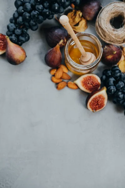 Espacio para texto, uvas negras, higos, miel y almendras en una b gris — Foto de Stock