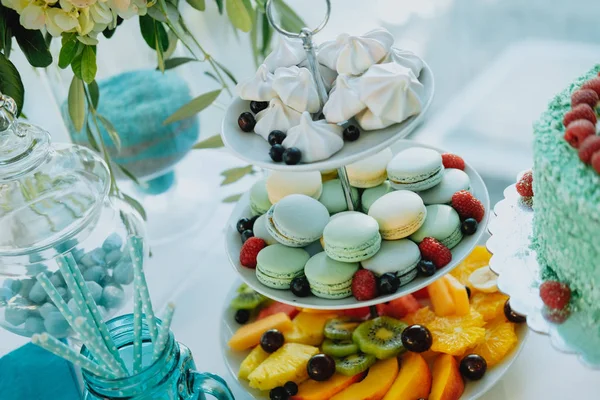 Mesa dulce con macarrones coloridos, frutas y pastel —  Fotos de Stock