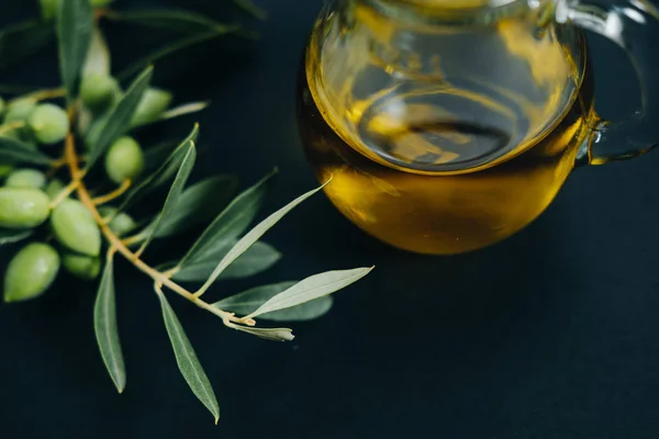 Primer plano Aceitunas, aceite y rama verde sobre fondo negro — Foto de Stock