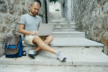 Serbest meslek sahibi adam ve sokağın ortasında bir dizüstü bilgisayar üzerinde çalışan bir gezgin