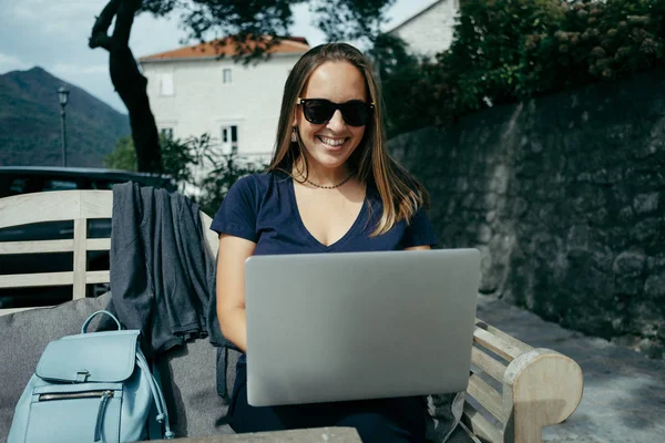 Обаятельная женщина-дизайнер в солнцезащитных очках, работающая с ноутбуком — стоковое фото