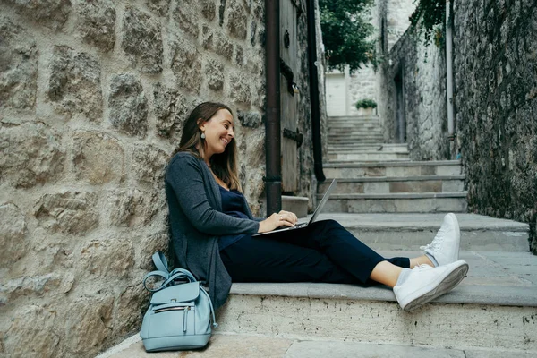 Vrouw freelancer in donker blauw vest op laptop bezig met de — Stockfoto