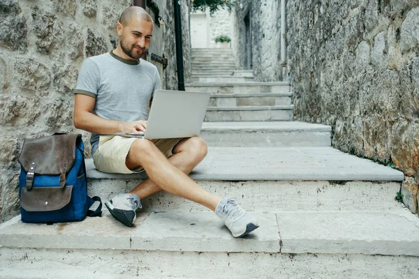 Serbest meslek sahibi adam ve sokağın ortasında bir dizüstü bilgisayar üzerinde çalışan bir gezgin