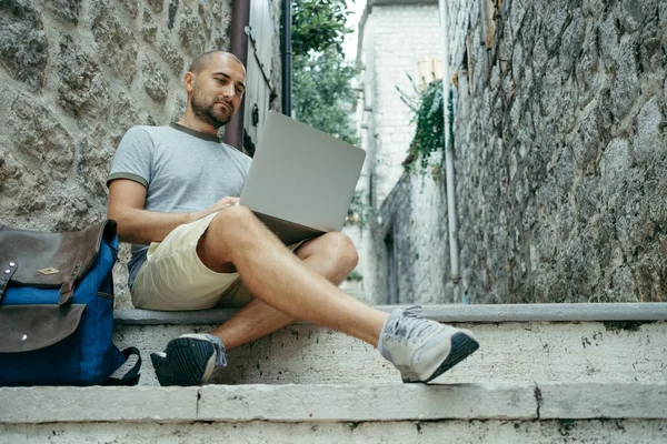 Serbest meslek sahibi adam ve sokağın ortasında bir dizüstü bilgisayar üzerinde çalışan bir gezgin