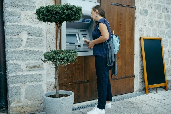 Vrouw reiziger haalt geld op een geldautomaat in Europa — Stockfoto