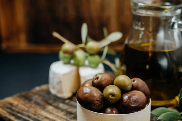 Sağlıklı snack: koyu ve yeşil zeytin, yağ, bir tahta üzerinde keçi peyniri — Stok fotoğraf