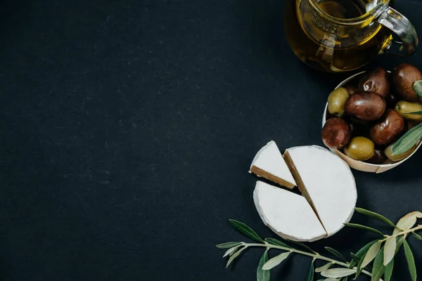 Snack saludable: aceitunas oscuras y verdes, aceite, queso de cabra en negro — Foto de Stock