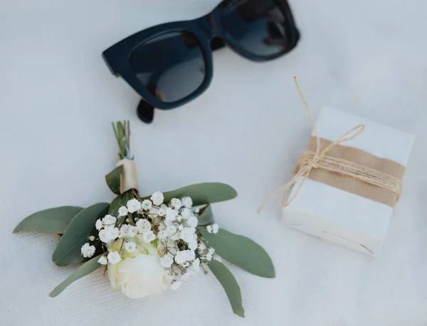 Óculos de sol, butanier e caixa de presente na mesa branca — Fotografia de Stock
