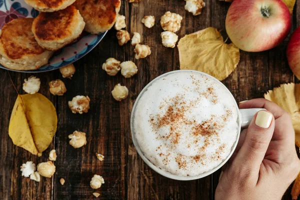 Patlamış mısır, elma, kek, le ile sıcak cappuccino ile kadının el — Stok fotoğraf