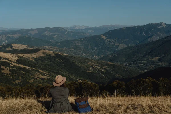 Arkadan Görünüm genç kadın Gezgin şapkalı bir tepenin arka tarafta oturur