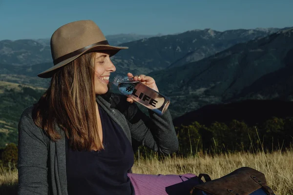 Mutlu genç kadın gezgin bir şapka içme suyu backgr içinde