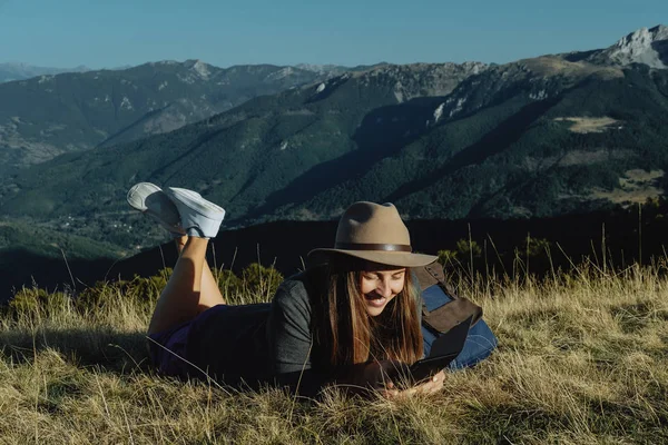 Mladá žena cestovatele v klobouku, čtení e knihy v poza — Stock fotografie