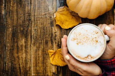 Kadın elleriyle sütlü Balkabağı ve ahşap backgr kuru yapraklar