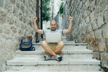 Serbest meslek sahibi adam ve sokağın ortasında bir dizüstü bilgisayar üzerinde çalışan bir gezgin