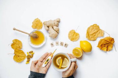 Çay ve termometre, ahşap kelime hasta, limon ile eller, 