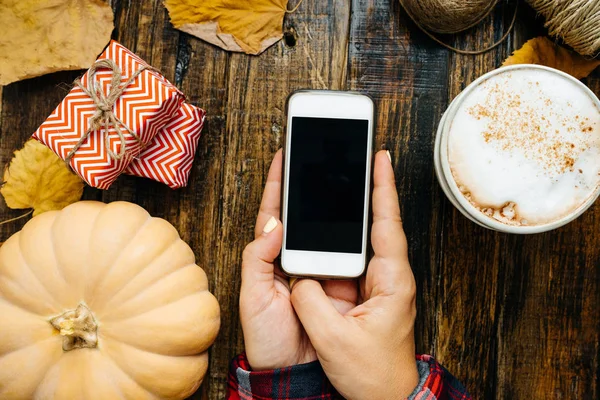 Bir ahşap tahta üzerinde siyah bir ekran ile bir telefon ile eller.