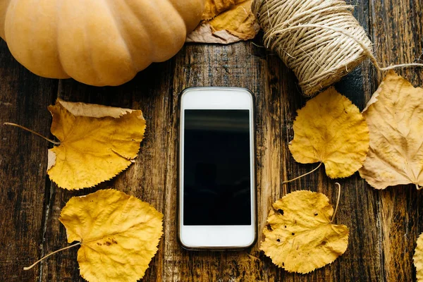 Bir ahşap tahta üzerinde siyah bir ekran ile telefon. Sonbahar kompozisyon: