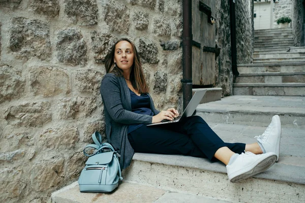 Mujer freelancer en cárdigan azul oscuro trabajando en el portátil en el — Foto de Stock