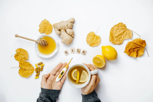 Manos de mujer con té y termómetro, Palabra de madera enferma, limón, t — Foto de Stock