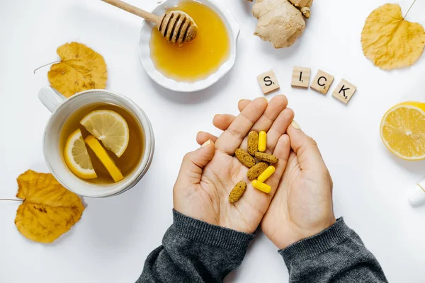 Mãos de mulher com comprimidos, chá, palavra de madeira doente, limão, termome — Fotografia de Stock