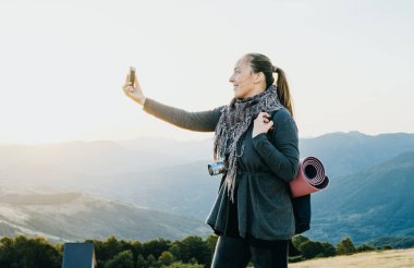 Kadın Gezgin fotoğraf telefon dağlardaki şafakta çeker