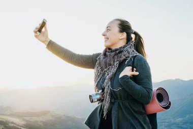 Kadın Gezgin fotoğraf telefon dağlardaki şafakta çeker