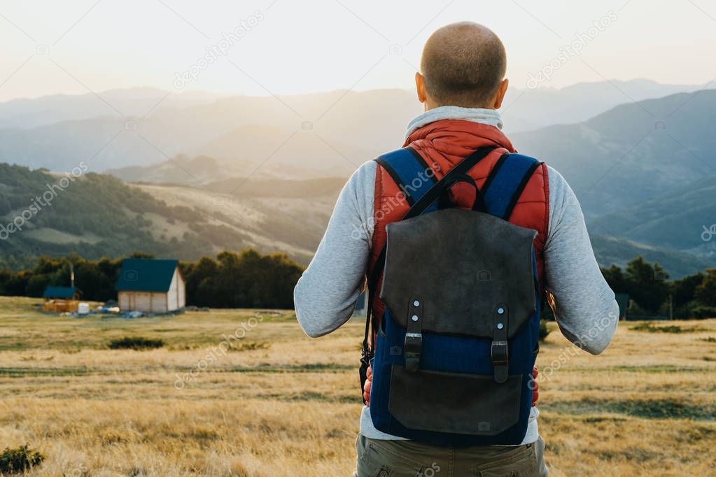 Back view of Hiker with backpack standing and looking at mountai