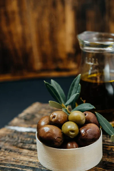 Aceitunas, aceite y rama verde sobre fondo de madera — Foto de Stock