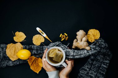 Kadınların elleri ile çay, limon, termometre, zencefil, eşarp, Masa