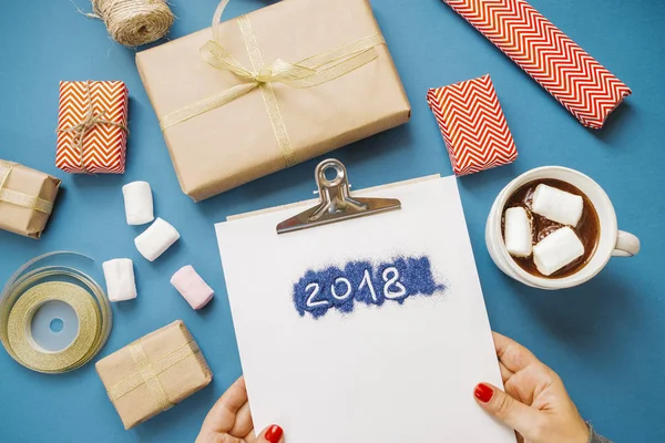 Women's hands with paper with the word 2018, hot cocoa with mars — Stock Photo, Image